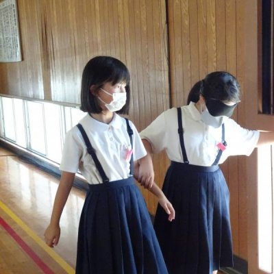 アイマスクをして友だちに誘導してもらう児童の画像