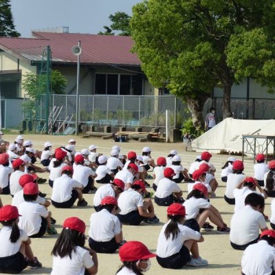 運動場で先生のお話を聞いている児童の画像